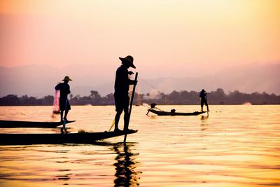 Silhouette fishermen against sky during sunset