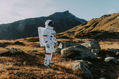 Man standing on rock against sky