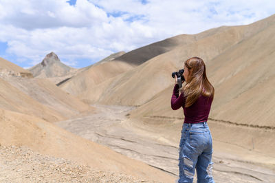 Rear view of man photographing against sky