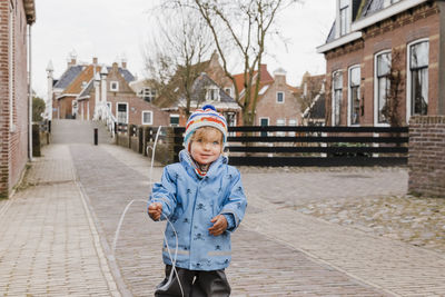 Portrait of boy standing against building