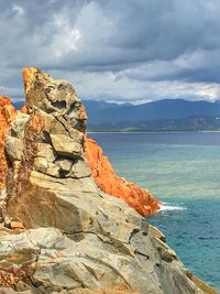 Rock formation on sea shore against sky