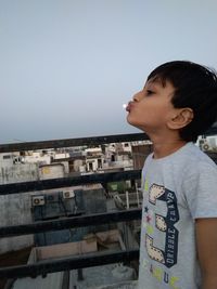 Boy looking at camera against clear sky