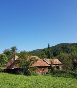 House on field against clear blue sky