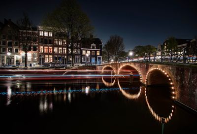 Reflection of illuminated buildings on calm river in city at night