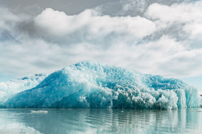 Iceberg floating in sea against sky