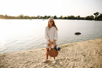 Portrait of young woman at beach against sky