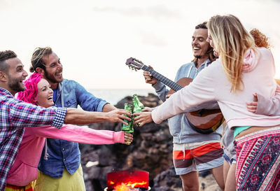 Happy friends toasting beer bottles at beach