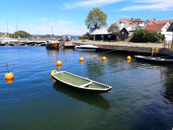 Sailboats moored on river by buildings against sky