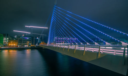 Illuminated bridge over river at night