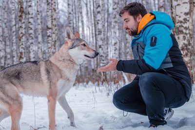 Side view of young man with dog in snow