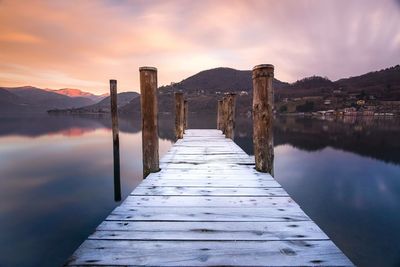 Pier over lake against sky during sunset