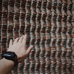 Cropped hand holding cigarette against wall