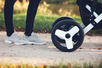 Low section of person standing with baby stroller on field