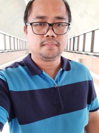 Portrait of man wearing eyeglasses standing in corridor of building