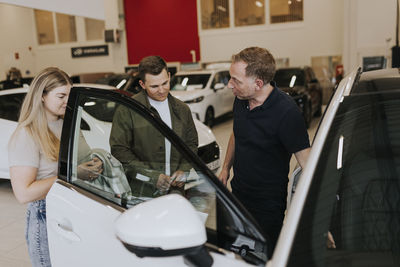 Salesman talking to customers in car dealership