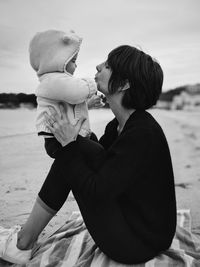 Side view of mother holding baby girl at beach