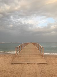 Wooden pier on beach against sky