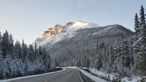 Road amidst snowcapped mountains against sky