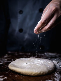 Midsection of chef spreading flour on dough in kitchen