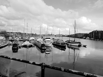 Boats moored at harbor against sky