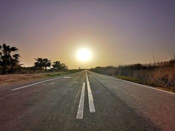 Empty road against sky during sunset