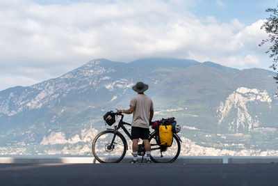 Rear view of man riding bicycle on snowcapped mountain