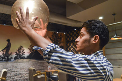 Side view of man looking at illuminated lamp