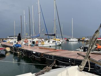 Sailboats moored at harbor against sky