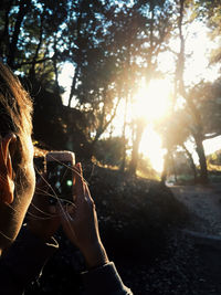 Man photographing through smart phone on tree