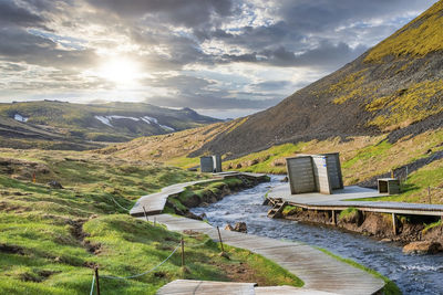 View of boardwalk and changing rooms by hot stream in hveragerdi against sky