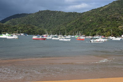 Sailboats moored on sea against mountains