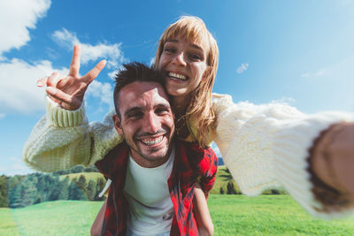 Portrait of happy friends smiling against sky