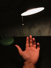 Close-up of hand on illuminated lamp