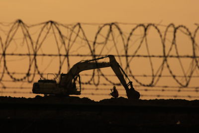 Silhouette construction site against sky during sunset