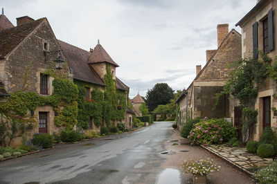 Road amidst houses in town against sky