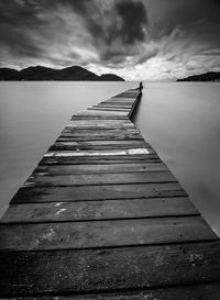 Boardwalk over lake against sky