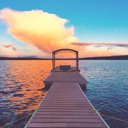 Pier amidst lake against sky during sunset