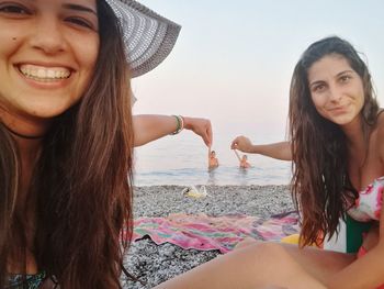 Portrait of smiling young woman at beach against sky