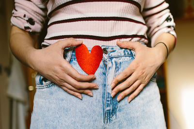 Midsection of woman holding heart shape