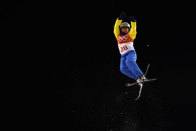 Full length of man with arms raised against black background