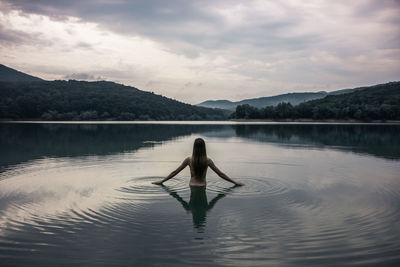 Rear view of man on lake against sky