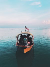 People on boat in sea against sky