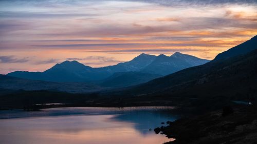 Scenic view of lake and mountains against sky during sunset