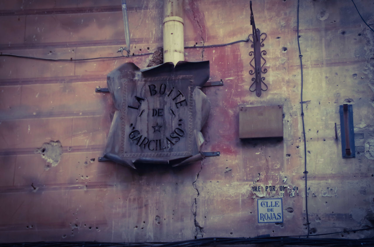 architecture, built structure, text, wall - building feature, communication, building exterior, western script, low angle view, door, abandoned, wall, old, no people, graffiti, day, outdoors, metal, close-up, weathered, house