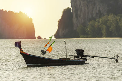 Man fishing on sea against sky during sunset