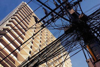 Low angle view of cables against building on sunny day