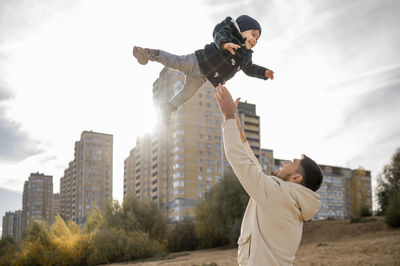 Father catching and playing with son at beach on sunny day