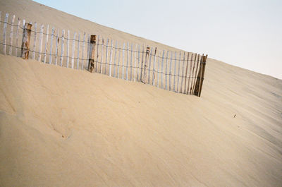 Fence on beach against clear sky