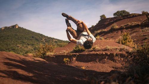 Side view of man jumping against sky