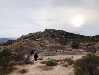 Rear view of man walking on cliff against sky
